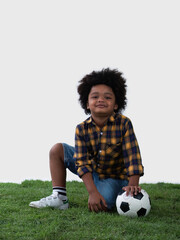Little African boy sitting with football on the grass with white background.