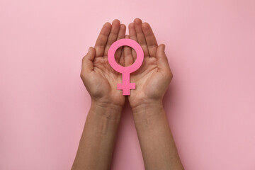 Woman holding female gender sign on pink background, top view
