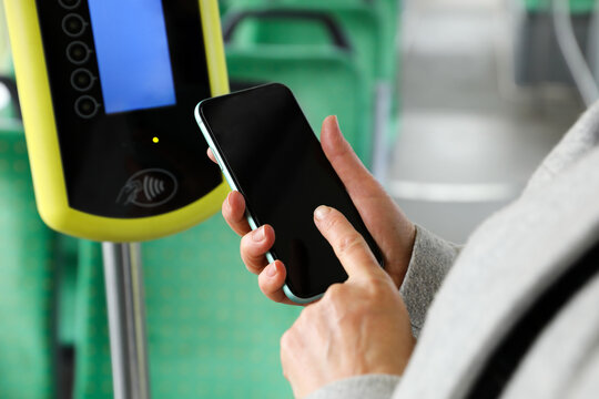 Woman with smartphone near contactless fare payment device in public transport, closeup