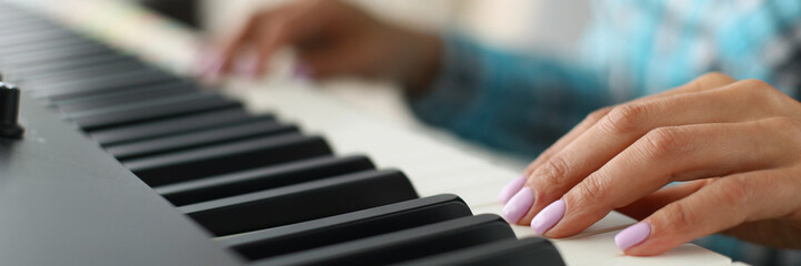 Womans hand touching white and black keyboards on piano