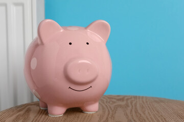 Piggy bank on wooden table near heating radiator, space for text