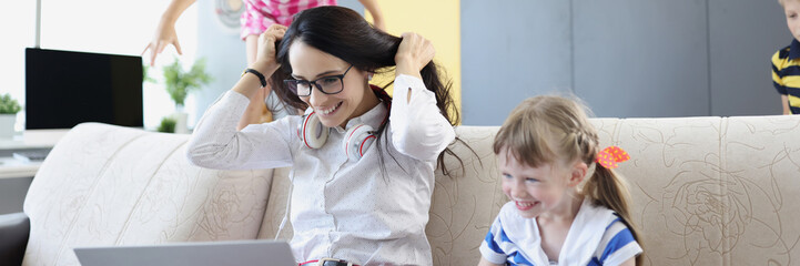 Happy woman working and playing with her kids on couch