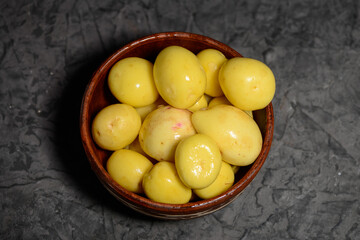 fresh peeled young potatoes in a clay plate on a gray background macro
