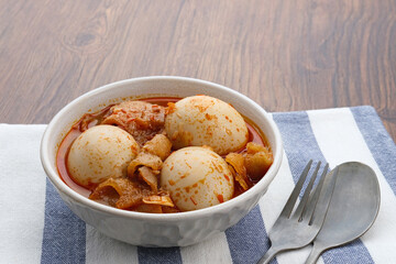 Sambal Goreng Telur Krecek, is javanese traditional food. Served in white bowl on wooden table. Seasoned with chilies and spices, spicy and delicious. A popular meal during Eid al-Fitri
