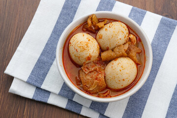 Sambal Goreng Telur Krecek, is javanese traditional food. Served in white bowl on wooden table. Seasoned with chilies and spices, spicy and delicious. A popular meal during Eid al-Fitri
