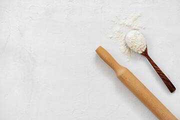 Fototapeta na wymiar Pile of flour in wooden spoon on white background