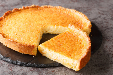 One of the creamiest mixtures of gooey sour and sweet, this Southern buttermilk pie closeup in a slate plate on the table. Horizontal