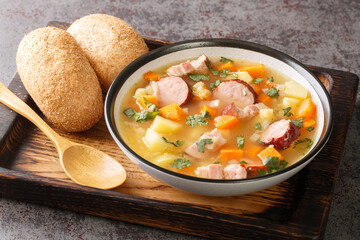 Polish Grochowka Pea soup with potatoes, onions, carrots, bacon and sausages close-up in a bowl on the table. Horizontal