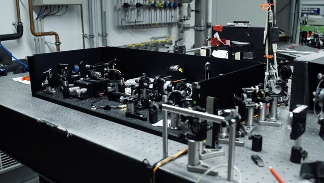 Horizontal pan over an optical table with different laser and mirror elements for precise scientific measurements