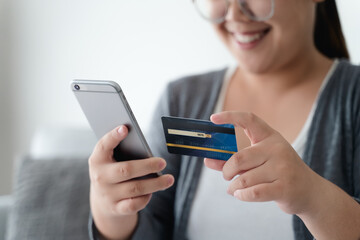 Woman holding credit card and using smartphone for online shopping, internet banking, e-commerce, spending money.