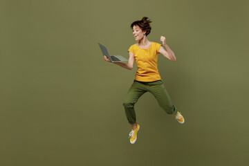 Full body young woman she 20s wear yellow t-shirt jump high run hold use work on laptop pc computer...