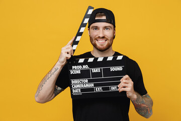 Young smiling bearded tattooed man 20s he wears casual black t-shirt cap holding classic black film...