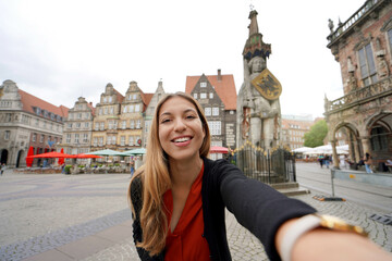 Beautiful woman takes self portrait in Bremen Market Square with Roland statue, Bremen, Germany - obrazy, fototapety, plakaty