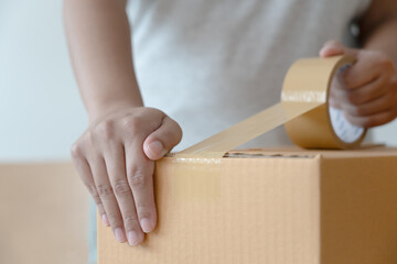 Woman sealing tape cardboard box preparing to delivery. Parcel in packing process to shipping...