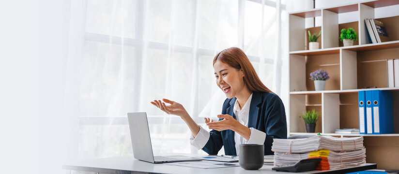 Young attractive Asian business woman feeling surprised, shocked when read the best news on laptop computer.