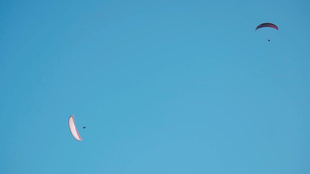 Group of tourists paragliding on parachute in blue sky background  during winter at Manali in Himachal Pradesh, India. Tourists lifting off from the mountain for paragliding experience.