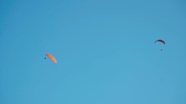 Group of tourists paragliding on parachute in blue sky background  during winter at Manali in Himachal Pradesh, India. Tourists lifting off from the mountain for paragliding experience.