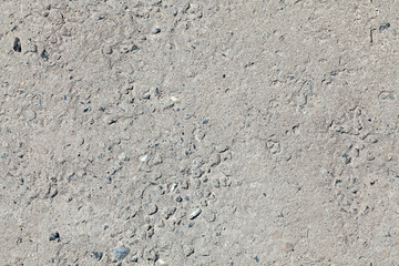 Absolutely seamless texture of rough gray asphalt with stones