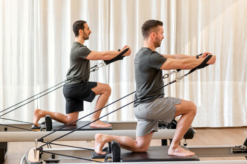 Men doing pilates exercise on reformer bed