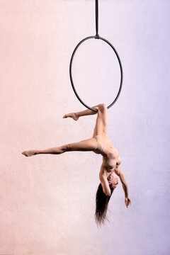 Flexible aerialist performing trick on aerial hoop