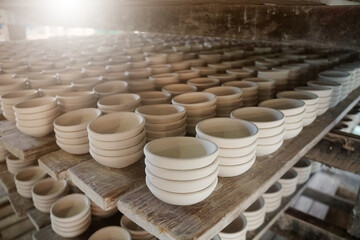 Raw vintage style kaolin cups or China clay cups are arranged in rows on the shelf. How to make the traditional ceramic pottery.