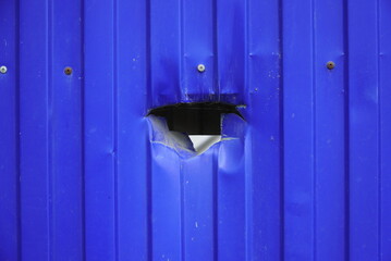 a fragment of a fence made of a blue stamped sheet of metal, with a punched hole.