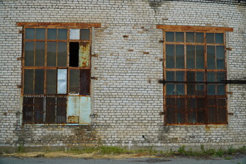 Two large old windows of an abandoned factory. Lattice on the broken windows.