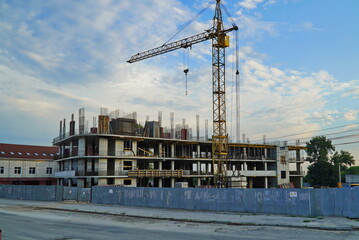 The big tower crane on building of shopping centre against the sky