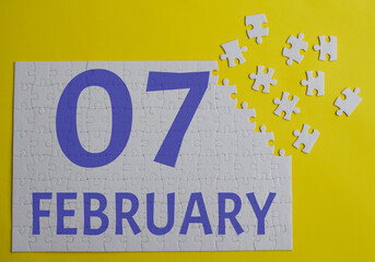 7 february calendar date on a white puzzle with separate details. Puzzle on a yellow background with a blue inscription