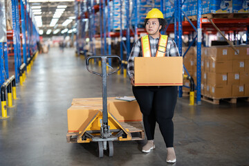 Overweight fat cholesterol woman in large warehouse  with high level of warehouse steel blue racking pulling hand pallet truck lift up the box looking around to find correct storage scan location
