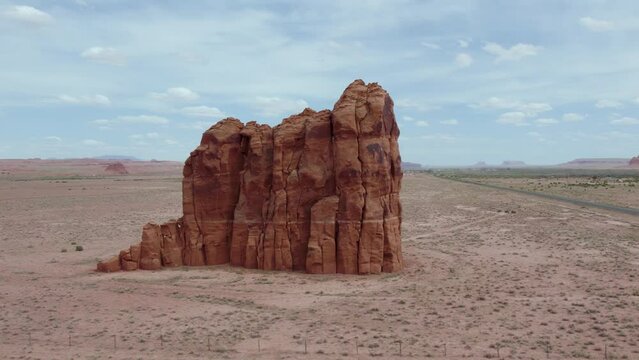 Eroded Rock Formation Standing Amidst Desert By The Road In Apache County, Arizona, United States. Aerial Orbiting