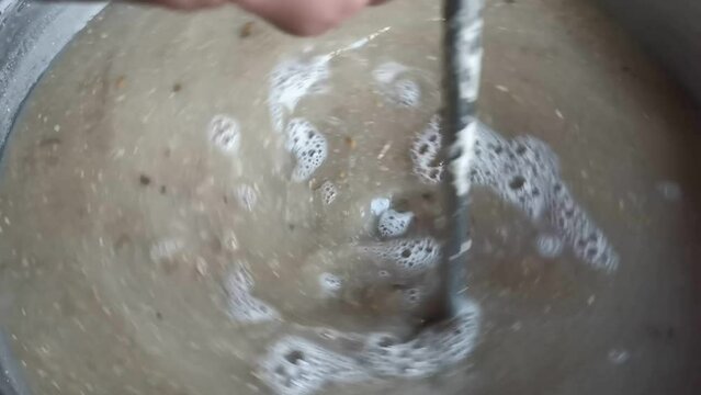 Stirring the malt and water mixture during the mashing procedure of a home brewed pilsner. Slow motion detail shot