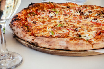 Greek pizza and cold white wine glass in outdoor restaurant. Tourist dinner in Agios Nikolaos in Crete, Greece. Summer vacation concept.