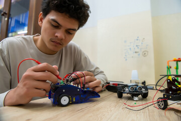 Fototapeta Teenage students build learning with robotic vehicles at desks in STEM engineering science education classes. obraz