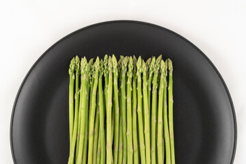 Fresh asparagus in dish  on white background. Top view. Vegan healthy food.