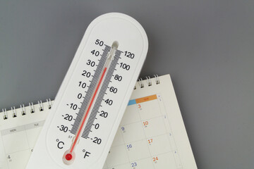 Weather forecast and climate changing. Thermometer with calendar on gray background.