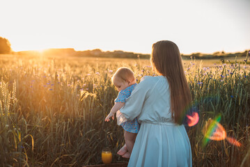 mother and daughter having a picnic outdoors in the field. Playing and having fun with little baby . Happy family concept