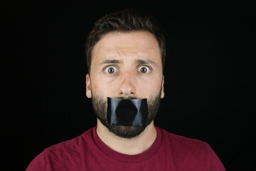 Young caucasian man can't speak, black tape on the mouth. 