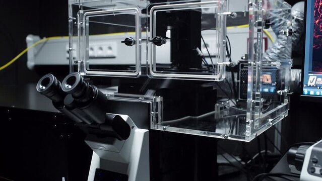 Pan down to a modern microscope model with a plexiglass box to hold the specimen