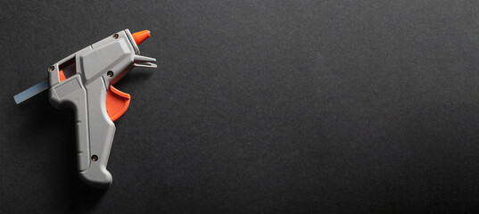 Gray and orange hot glue gun on a dark background