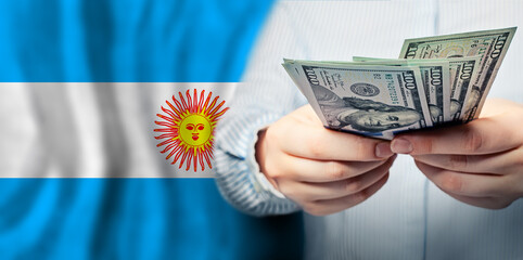 Close up dollars cash money in hand on flag of Argentina background