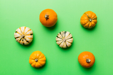 Autumn composition of little orange pumpkins on colored table background. Fall, Halloween and Thanksgiving concept. Autumn flat lay photography. Top view vith copy space