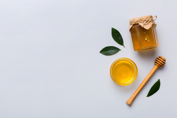 Honey jar with wooden honey dipper on white background top view with copy space. Delicious honey...