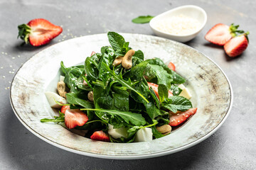 salad with strawberry, spinach leaves and feta cheese on gray stone background Fresh vegetarian snack, banner, menu, recipe place for text, top view