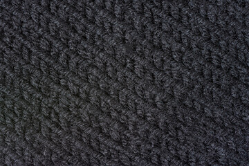 Knitted texture background. Hand-knitted wool. Macrophotography of a thread drawing. Black pastel texture of sweaters, pullovers, cardigans. Abstract natural background. Comfort autumn warmth concept