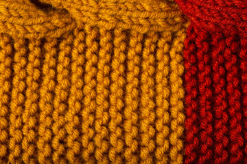 Knitted texture background. Hand-knitted wool. Macrophotography of a thread drawing. Orange-red texture of sweater, pullover, cardigan. Abstract natural background. Comfort autumn warmth concept