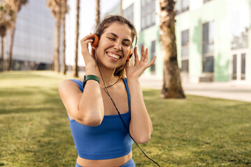 Happy young caucasian lady listens to music with her eyes closed relaxing after workout outdoors....
