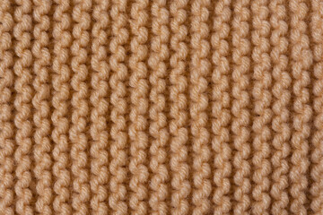 Knitted texture background. Hand-knitted wool. Macrophotography of a thread drawing. Beige pastel texture of sweaters, pullovers, cardigans. Abstract natural background. Comfort autumn warmth concept