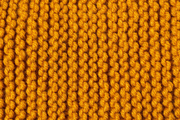 Knitted texture background. Hand-knitted wool. Macrophotography of a thread drawing. Orange pastel texture of sweaters, pullovers, cardigans. Abstract natural background. Comfort autumn warmth concept