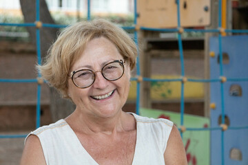 Blonde Caucasian woman in her 60s looking at camera and laughing because she is happy because it is...